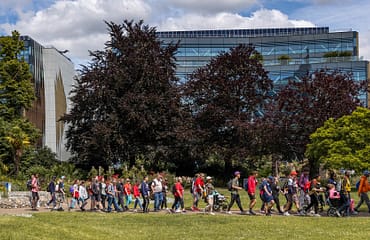 A line of people walking through Forbury Gardens