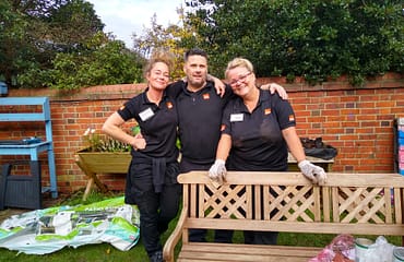 A man and two women wearing B&Q t-shirts are standing in the Reading Mencap garden