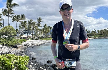Trustee JIm Allpass stands on the banks of a lake and displays his medal