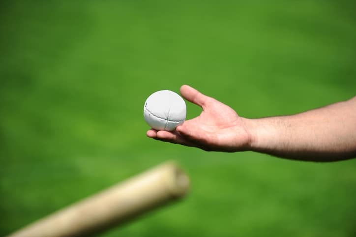 Hand holding a rounders ball. Rounders is a bat and ball game between two team that involves hitting a hard leather cased ball with a wooden bat.