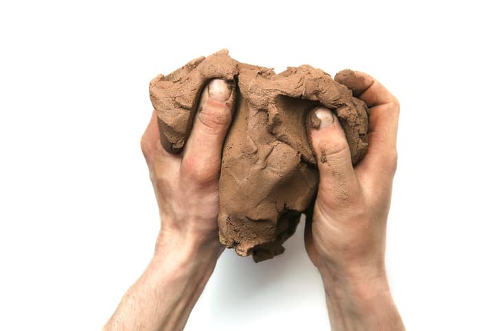 A lump of clay is being held in a pair of hands,